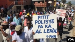Para polisi Haiti yang berdemo mengacungkan poster bertuliskan "Anak-anak polisi tidak bisa bersekolah" di Port au Prince, Haiti, 27 Oktober 2019. (Matiado Vilme / VOA Creole) 