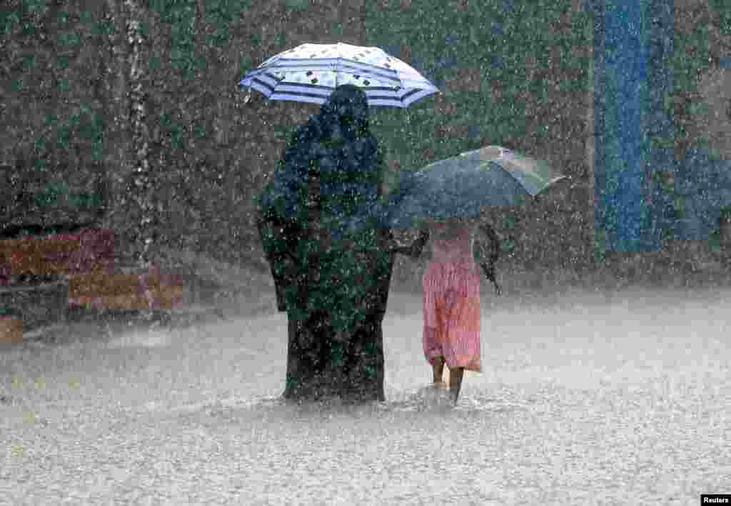A woman walks with a girl along a flooded road in the heavy rains in Malwana, Sri Lanka.