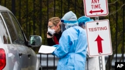 Medical personnel from Montgomery County, Md., check patients arriving for a COVID-19 drive-in testing in Silver Spring, April 21, 2020. 