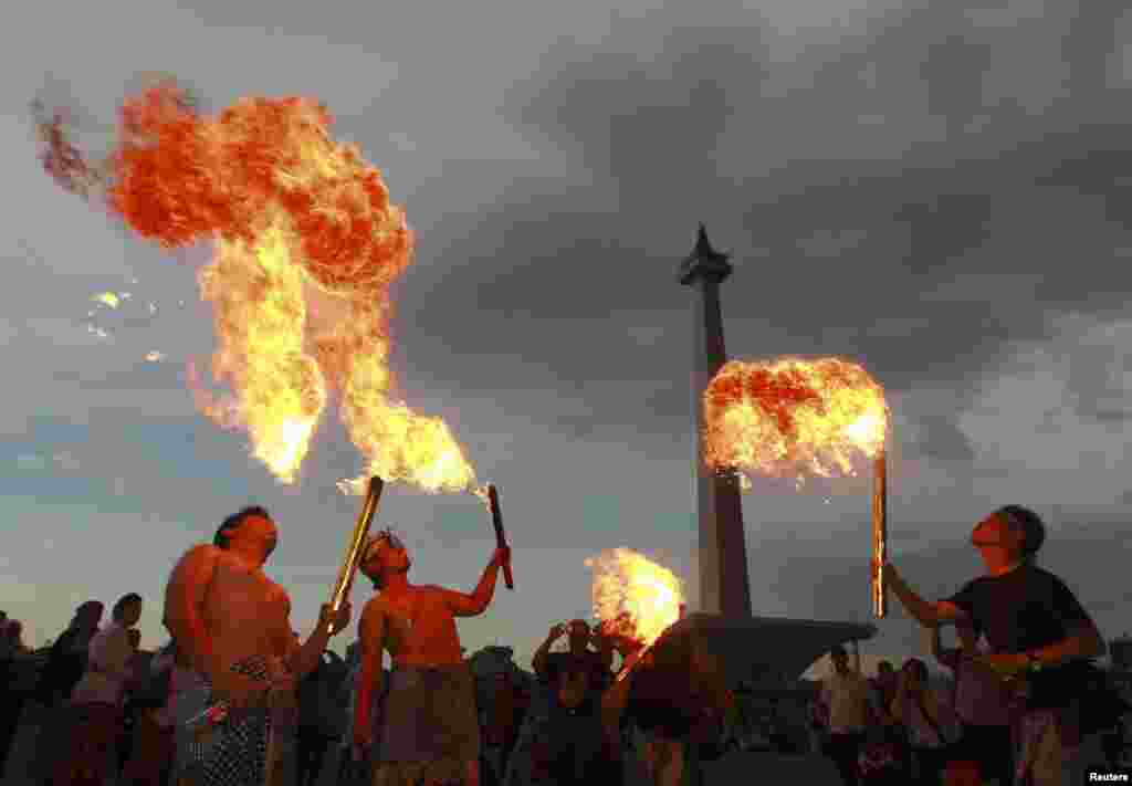 Beberapa orang penganut Hindu membawa api dalam ritual sebelum hari raya Nyepi, dekat Monumen Nasional di Jakarta. Selama Nyepi, warga Hindu Bali dilarang menggunakan lampu, menyalakan api, bekerja, melakukan perjalanan atau menikmati hiburan.