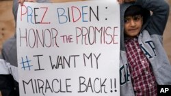 FILE - Demonstrators hold signs calling for the White House to reconsider admitting visa lottery winners who were denied access during the previous administration, in the Bronx borough of New York, March 24, 2021.