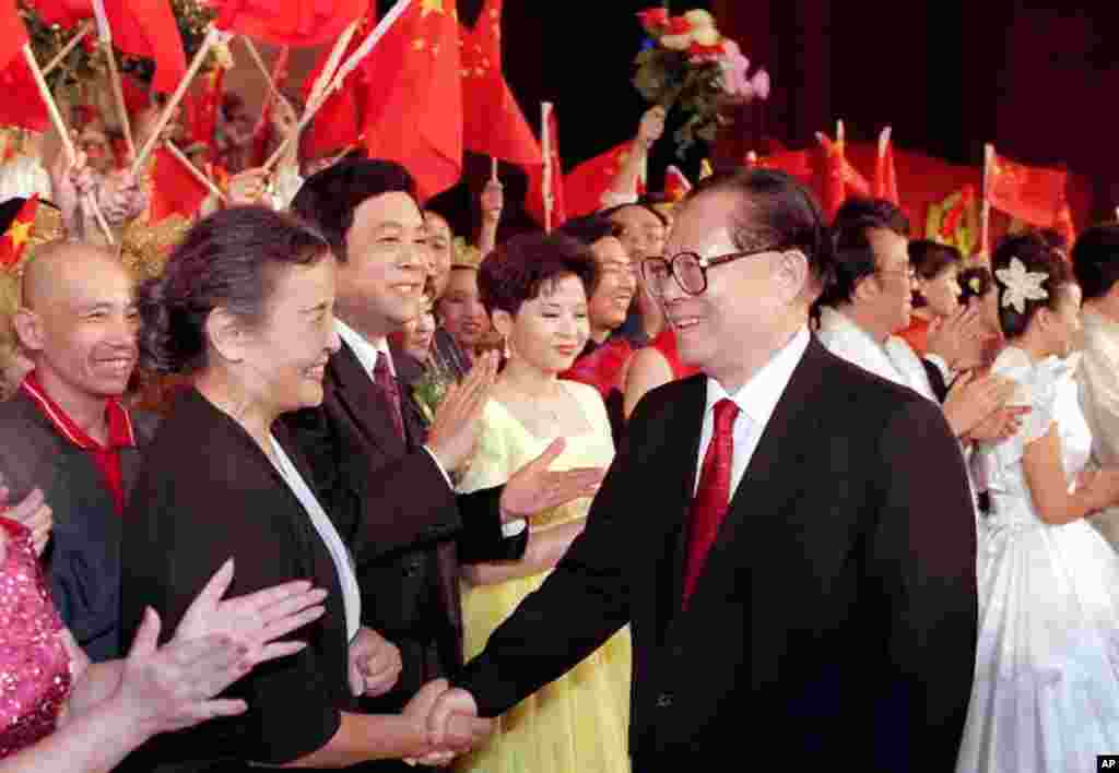 1999年9月28日，在北京的文艺演出“祖国颂”之后，中国主席江泽民和乐团指挥郑小英握手。其他在场者似乎有（左起）京剧演员孟广禄、播音员赵忠祥和歌唱家董文华。