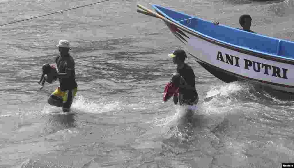 Para nelayan membawa jenazah anak-anak yang menumpang kapal berisi pencari suaka yang terbalik akibat menghantam karang (24/7).