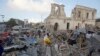 Locals walk through debris of a destroyed building following a twin car bomb attack in Mogadishu, Somalia, Feb. 24, 2018.