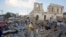 Locals walk through debris of a destroyed building following a twin car bomb attack in Mogadishu, Somalia, Feb. 24, 2018.