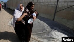 30일 가자지구 남부에 이스라엘의 폭격이 있은 후, 팔레스타인 여성이 갓난아이를 데리고 대피하고 있다.