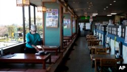 A server with a mask cleans a table at a restaurant in Fujisawa, Japan, Thursday, Feb. 27, 2020. According to local businesses in the area, the number of visitors has dropped significantly since the outbreak of COVID-19. (AP Photo/Jae C. Hong)
