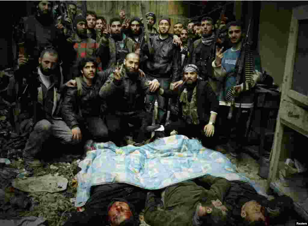 Free Syrian Army fighters pose next to bodies in Homs, March 3, 2013.