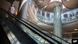 2022年5月21日，一名戴着口罩的女子在北京一家空空荡荡的商场里的自动扶梯上。