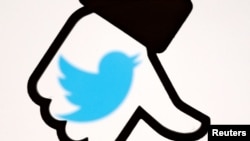 FILE - A 3D-printed Facebook dislike button is seen in front of a displayed Twitter logo in this illustration taken Oct. 25, 2017. 