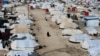 FILE - A woman walks through al-Hol displacement camp in Syria April 2, 2019.