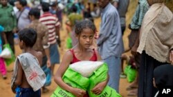 A newly arrived Rohingya girl carries food rations in Kutupalong, Bangladesh, Saturday, Sept. 30, 2017. 