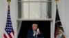 President Donald Trump removes his face mask to speak from the Blue Room Balcony of the White House to a crowd of supporters, Oct. 10, 2020, in Washington.