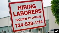 FILE - A sign seeking to hire laborers is posted outside a concrete products company in Evans City, Pennsylvania, May 5, 2021. 