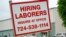 FILE - A sign seeking to hire laborers is posted outside a concrete products company in Evans City, Pennsylvania, May 5, 2021. 