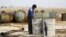 FILE - A youth works at a makeshift oil refinery in the countryside south of Idlib, Syria. 