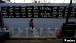 عبور رهگذران از کنار تابلویی برای یادبود قربانیان بمب گذاری ۱۹۹۴ در آرژانتین