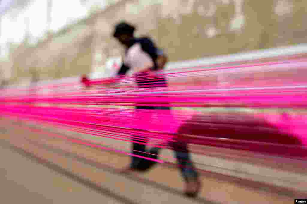 បុរស​ម្នាក់​លាប​ពណ៌​លើ​ខ្សែ​ខ្លែង​នៅ​តាម​ដង​ផ្លូវ​មួយ​ ក្នុង​ក្រុង Ahmedabad ប្រទេស​ឥណ្ឌា។&nbsp;