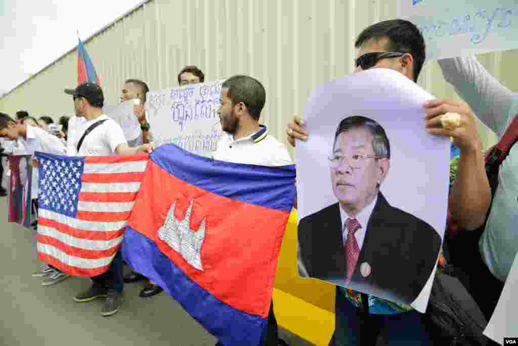 សន្តិសុខ​ដែល​ត្រូវ​បាន​ស្ថានទូត​សហរដ្ឋ​អាមេរិក​បញ្ឈប់​កាល​ពី​ប៉ុន្មាន​ខែ​មុន​​​និង​គ្រួសារ​របស់ពួកគេ​បាន​មក​ធ្វើ​បាតុកម្ម​តវ៉ា​រក​យុត្តិធម៌​ដោយ​អហិង្សា​នៅ​ខាង​មុខ​ស្ថានទូត​អាមេរិករាជធានី​ភ្នំពេញ​ ​កាល​ពីព្រឹក​ថ្ងៃទី​១៩ មិថុនា ឆ្នាំ ២០១៨។(ទុំ ម្លិះ/VOA)