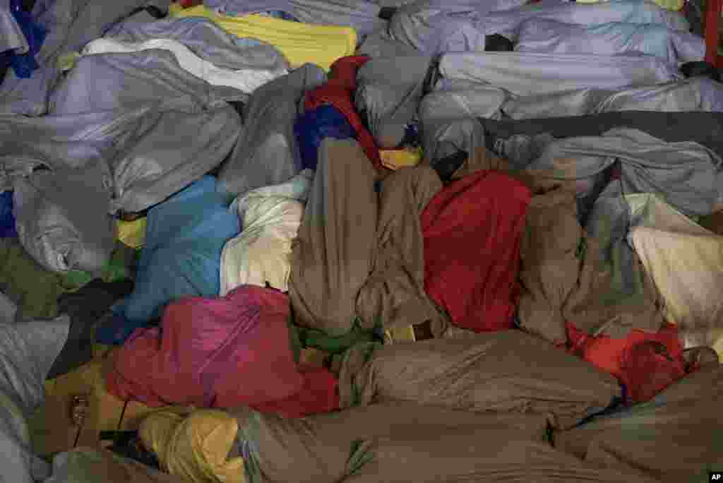 Para migran dan pengungsi istirahat di geladak kapal setelah diselamatkan dari perahu mereka di lepat pantai Libya, Laut Tengah.