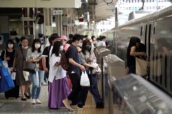 Passengers wearing face masks to help curb the spread of the coronavirus board a westbound bullet train at Tokyo Station in Tokyo, July 31, 2021.