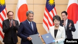 2023年12月16日，在日本东京首相官邸举行的签字仪式后，日本外相上川洋子（前右）与马来西亚外长穆罕默德·哈桑（前左）合影。（路透社）
