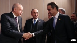 A Turkish Presidential Press photos shows Turkey's President Recep Tayyip Erdogan, left, and Greek Prime Minister Kyriakos Mitsotakis shaking hands during a meeting at the NATO summit in London, Dec. 4, 2019.