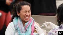 Ana Farfan reacts to getting an influenza vaccine shot at Eastfield College in Mesquite, Texas, Jan. 23, 2020. 