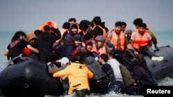 Sejumlah migran yang berupaya untuk mencapai Inggris dengan menyeberangi Selat Inggris, naik ke atas perahu karet yang berangkat dari wilayah Wimereux, Prancis, pada 4 September 2024. (Foto: Reuters/Benoit Tessier)