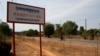 A man rides a motorcycle past a signboard for the Cambodia Iron Group at the Rovieng District in Preah Vihear province, February 10, 2013.