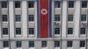 FILE - A pedestrian walks past a North Korean flag displayed on a building in Pyongyang, North Korea, April 12, 2019.