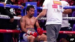 FILE - Trainer Freddie Roach speaks to Manny Pacquiao between rounds against Yordenis Ugas, of Cuba, in a welterweight championship boxing match in Las Vegas, Aug. 21, 2021. Pacquiao is officially hanging up his gloves. FILE - Trainer Freddie Roach speaks
