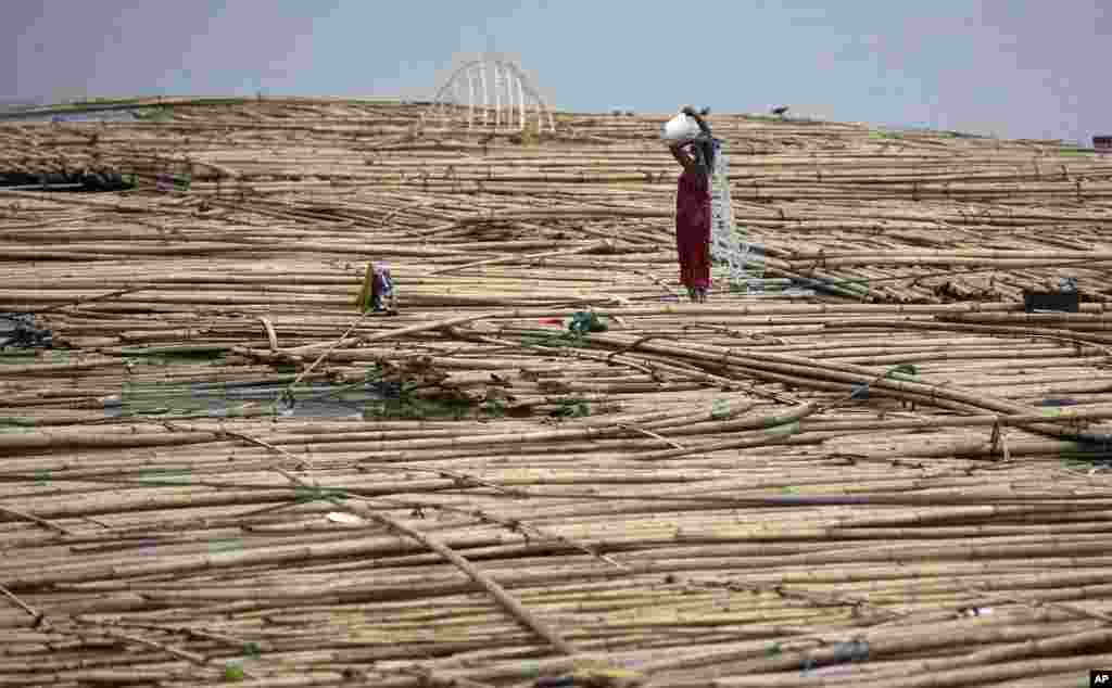 Seorang wanita mandi di antara bambu-bambu yang terapung di Sungai Brahmaputra di Gauhati, India.