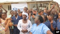 感染了埃博拉病毒的雅丹玛·桑科（中）获得治愈后在离开塞拉利昂一个埃博拉治疗中心时与医疗人员在一起。 （2015年8月24日）