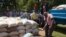 Flood survivors offload bags of maize, ready for distribution. (L. Mesina for VOA)