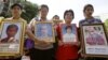 Relatives of the victims hold portraits of their loved ones during a commemorate session of a rally at Ratchaprasong Intersection in Bangkok, Thailand, May 19, 2012.