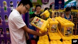 2013年7月25日，在北京玩博会上，中国游客查看参展的塑料积木。最新数据显示，中国经济出现好转迹象，但内需仍有待加强。