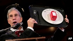 Master of Ceremonies Marc Abrahams holds up the 2014 Ig Nobel Prize trophy during a performance at the Ig Nobel Prize ceremony at Harvard University, in Cambridge, Mass., Sept. 18, 2014. 