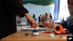 An Afghan woman, left, inks her finger at a polling station at Amani high school, near the presidential palace in Kabul, Afghanistan, Sept. 28, 2019.