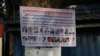 A poster plastered on a tree displays 18 senior CNRP leaders wanted for arrest in Poipet, Banteay Meanchey province, on Nov 7, 2019. (Sun Narin/VOA Khmer)