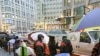 Apple customers use umbrellas as they wait in line at an Apple store on the first day of the launch of the new iPad, in San Francisco, March 16, 2012. 