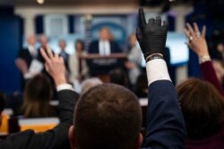 Reporters raise their hands to ask President Donald Trump questions during a press briefing with the coronavirus task force, at the White House, March 16, 2020.