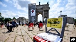 រូ​បឯកសារ៖ ស្លាកបដាមួយសរសេរថា «ប្រសិនបើយើងបើក​ យើងនឹងក្ស័យធ័ន» ស្របពេលម្ចាស់ភោជនីយដ្ឋាន​និងបារតវ៉ាពីការដាក់កំហិតលើការបើកសេដ្ឋកិច្ចសារជាថ្មីនៅក្រុង Milan ប្រទេសអ៊ីតាលី កាលពីថ្ងៃទី០៦ ខែឧសភា ឆ្នាំ២០២០។ 