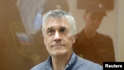FILE - Founder of the Baring Vostok private equity group Michael Calvey, who was detained on suspicion of fraud, sits inside a defendants' cage as he attends a court hearing in Moscow, Feb. 15, 2019.