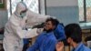 Un agent de santé prélève un échantillon sur un élève pour tester le coronavirus dans un lycée public à Lahore, au Pakistan, le 1er octobre 2020.