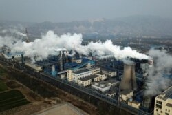 FILE - In this Nov. 28, 2019 file photo, smoke and steam rise from a coal processing plant in Hejin in central China's Shanxi Province.