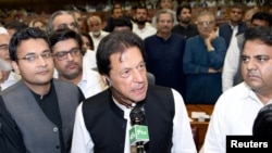 وزیراعظم عمران خان او د تصویر ښي لاس ته د اطلاعاتو وزیر فواد چودهري لیدل کیږي چې وي او ای ډیوه ته وایي حکومت د ١٨ ترمیم د ختمولو اراده نه لري