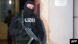 2014年1月16日，一名德国警官在柏林的一栋公寓对极端分子嫌疑人的住处进行搜查后站在这栋公寓外面站岗。