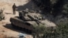 Seorang tentara Israel berdiri dekat tank di tengah bentrokan senjata antara Hizbullah dan Israel di utara Israel, 31 Oktober 2024. Kabinet Israel, Jumat, 1 November 2024, menyetujui anggaran 2025, termasuk kenaikan pajak untuk biayai perang. (Foto: Violeta Santos Moura/Reuters)