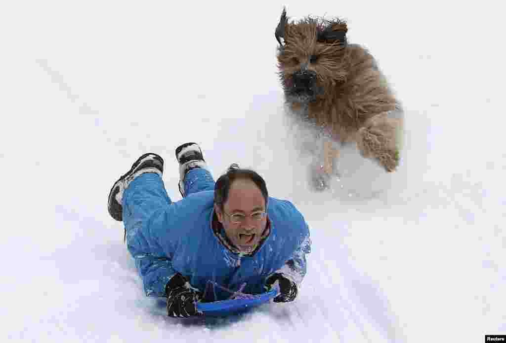 Seorang pria meluncur turun bukit di sebuah kereta luncur, dikejar oleh anjingnya di Central Park di New York. Badai salju melanda bagian timur laut Amerika Serikat, menewaskan setidaknya satu orang, mengakibatkan listrik mati di ratusan ribu orang dan membatalkan ribuan penerbangan.
